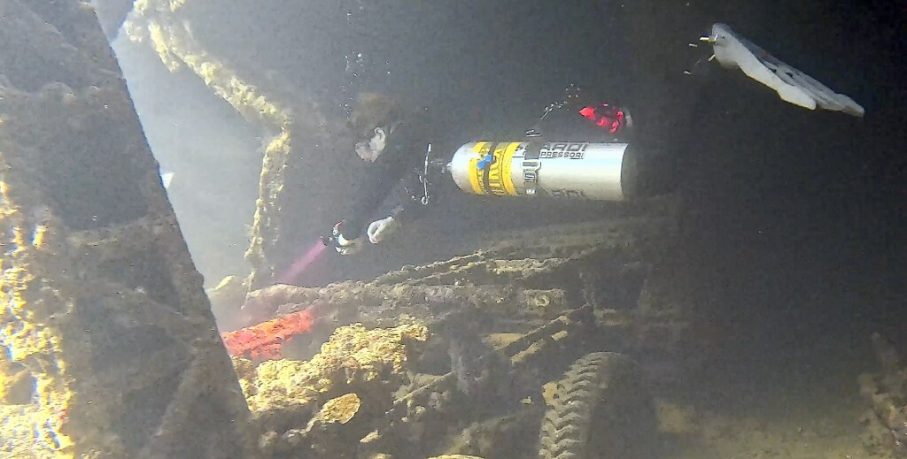 Malachi Jack exploring inside a submerged wreck in technical scuba equipment